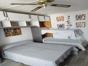 2 Betten in einem Zimmer mit Deckenventilator in der Unterkunft Salou Beach 1 in La Pineda