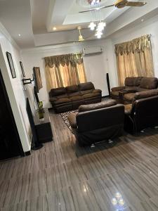 ein Wohnzimmer mit Ledersofas und einem TV in der Unterkunft BENJI'S VILLA in Kumasi