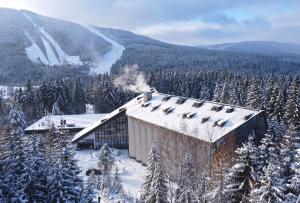 een gebouw midden in een met sneeuw bedekte berg bij Wellness Hotel Svornost in Harrachov