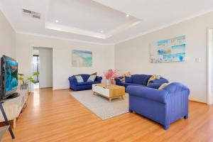 a living room with two blue couches and a tv at Daydream by the Sea! in Mandurah