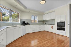 a kitchen with white cabinets and a wooden floor at Daydream by the Sea! in Mandurah
