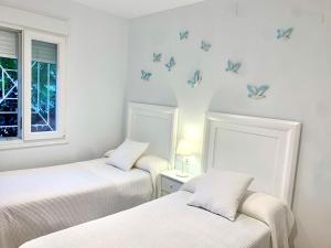 2 camas en una habitación con mariposas en la pared en Islantilla Luxury, en Isla Cristina