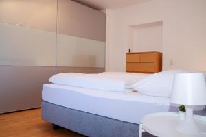 a bedroom with a white bed and a table at Appartement Bärhof in Innsbruck