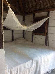a white bed with a net hanging over it at Beach front Cottage in Mahambo