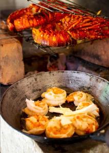 eine Pfanne gefüllt mit Garnelen und anderen Speisen auf einem Grill in der Unterkunft Beach front Cottage in Mahambo