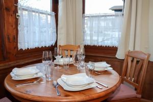 a wooden table with plates and wine glasses on it at Appartement Bärhof in Innsbruck