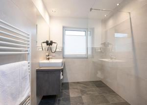 a white bathroom with a sink and a mirror at Hotel Brunner - Reiteralm in Schladming