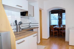 Appartement Bärhof في إنسبروك: مطبخ مع دواليب بيضاء وغرفة طعام