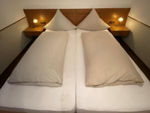 1 cama con sábanas blancas y almohadas en una habitación en Landschaftsgasthaus Schanze 1, en Schmallenberg