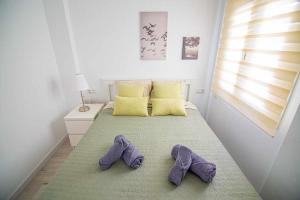 zwei Paar lila Hausschuhe auf einem Bett in einem Schlafzimmer in der Unterkunft New Apartamento centro de Torremolinos con Parking in Torremolinos
