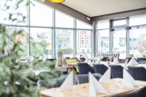 uma fila de mesas e cadeiras num restaurante com janelas em Select Hotel Elmshorn em Elmshorn