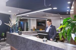 a woman standing at a counter with a laptop at Select Hotel Elmshorn in Elmshorn