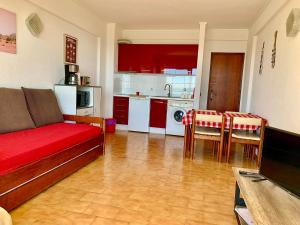 a living room with a red couch and a kitchen at Tubarinho Apartment in Costa da Caparica