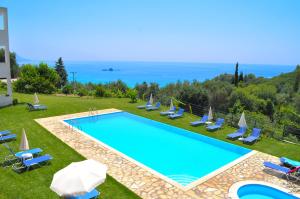 a swimming pool with chairs and umbrellas and the ocean at Large apartment by the pool - Pelekas Beach, Corfu in Pelekas