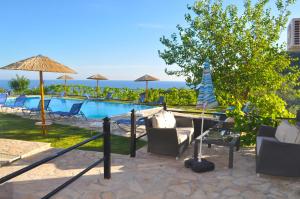 a pool with chairs and umbrellas and the ocean at Large apartment by the pool - Pelekas Beach, Corfu in Pelekas