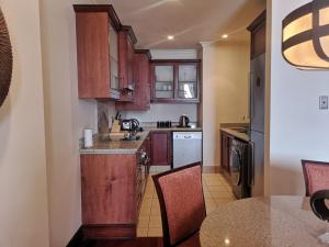 a kitchen with wooden cabinets and a table with chairs at Apartment at Michelangelo Towers in Johannesburg