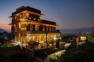 un grand bâtiment en bois avec des lumières allumées la nuit dans l'établissement Purna's Museum Resort, à Lalitpur
