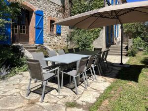 - une table avec des chaises et un parasol sur la terrasse dans l'établissement Gite la Tuilerie 46, à Tour-de-Faure
