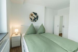 1 dormitorio con 1 cama con sábanas verdes y reloj en la pared en EASYLIFE - Apartment Relax, en Eisenach