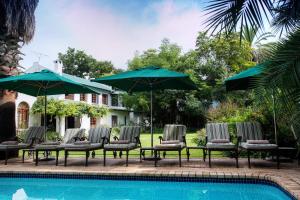 a group of chairs and umbrellas next to a pool at Woodall Country House and Spa in Addo