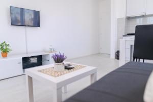 ein Wohnzimmer mit einem weißen Tisch und einem TV in der Unterkunft Apartman MASTER in Sokobanja