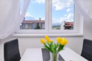 a vase of yellow flowers sitting in front of a window at Apartman MASTER in Soko Banja