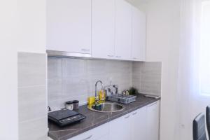 eine Küche mit weißen Schränken und einem Waschbecken in der Unterkunft Apartman MASTER in Sokobanja