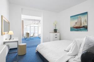 een witte slaapkamer met een bed en een schilderij van een zeilboot bij Black Pearl Tisno in Tisno