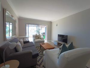 a living room with couches and a flat screen tv at The Aqua - Sleeps 4 - Patio & Sea Views in Plettenberg Bay