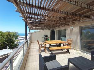 a patio with a wooden table and chairs on a balcony at The Aqua - Sleeps 4 - Patio & Sea Views in Plettenberg Bay