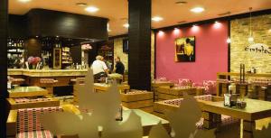 two people standing in a restaurant with a pink wall at Hotel · Restaurante Asador Tio Manolo in Noya +6 photos