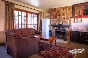 a living room with a couch and a table and a fireplace at Duckling Cottage in Dullstroom