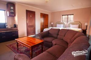 a living room with a couch and a bed at Duckling Cottage in Dullstroom