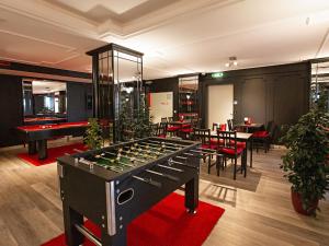 a room with a foosball table and some tables at DORMERO Hotel Burghausen in Burghausen