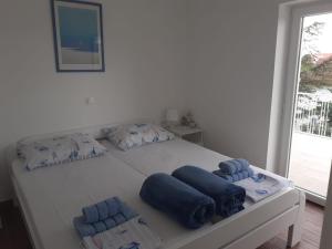 - un lit blanc avec des oreillers bleus dans l'établissement Apartment Nikica (with sea view, garden, parking), à Selce