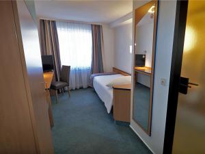 a hotel room with a bed and a window at Hotel Goldener Hirsch Mosbach in Mosbach