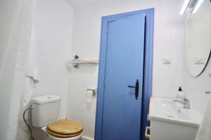 La salle de bains est pourvue de toilettes et d'une porte de douche bleue. dans l'établissement AranPe PLAYA CÁDIZ, à Cadix