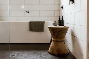a bathroom with a tub and two bottles of wine at The Villa at Bali Garden Matakana in Omaha