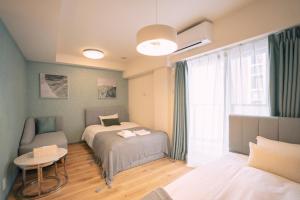 una camera da letto con due letti, un tavolo e una finestra di 谷町君HOTEL 心斎橋東32 ad Osaka
