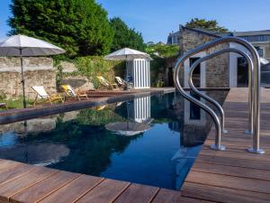 una piscina con sillas y sombrillas en una terraza de madera en HOTEL LA MARINE en Groix