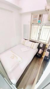 białe łóżko w pokoju z 2 oknami w obiekcie SAAN INN w Hongkongu