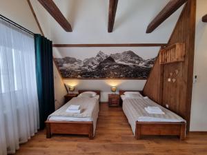 two beds in a room with a painting on the wall at Willa Silene - góralska muzyka na żywo i bezpłatne rowery do wypożyczenia in Bukowina Tatrzańska