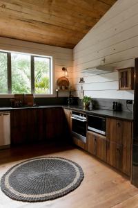a kitchen with wooden cabinets and a rug on the floor at The Villa at Bali Garden Matakana in Omaha