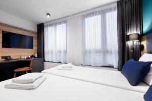 スタルガルトにあるKyriad Stargardのベッド2台、デスク、テレビが備わるホテルルームです。