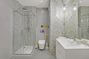 a bathroom with a shower and a sink and a toilet at Downtown Apartments Śląska 12 in Gdańsk