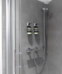 - une douche avec deux bouteilles de shampoing au mur dans l'établissement Modernes Apartment mit Queensize-Bett, NETFLIX, Küche, Erdgeschoss, Nähe AMEOS Klinik, à Aschersleben