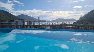 een groot zwembad met uitzicht op het water bij Apartamento Alto Padrão Ubatuba in Ubatuba