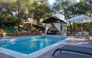 a swimming pool with a table and an umbrella at CASA RURAL HUERTO PERDIDO in Alosno