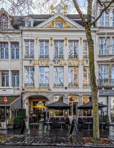 a hotel dmg with tables and umbrellas in front of it at Hotel Damier Kortrijk in Kortrijk