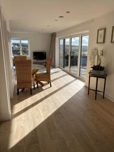 a living room with a table and chairs and windows at Spacious Studio Cabin with Sea/ Downs views Sole Use of HotTub in Seaford in Seaford